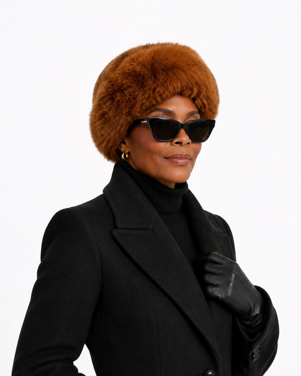 A woman wearing a voluminous, warm brown Alpaca fur hat, black sunglasses, a black turtleneck, a black coat, and a black glove, photographed against a solid white background.